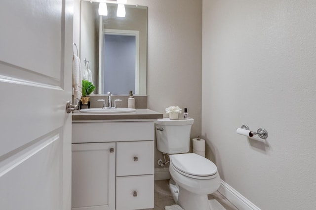 half bathroom featuring toilet, vanity, and baseboards