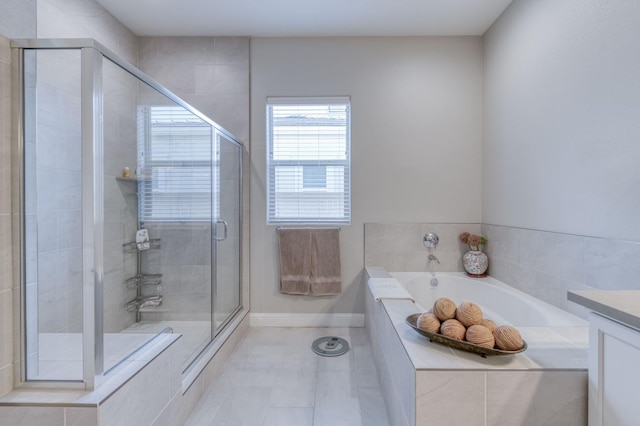 bathroom featuring tile patterned flooring, vanity, baseboards, a bath, and a stall shower