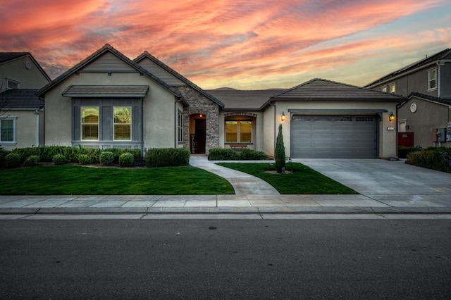 view of front of home with stucco siding, concrete driveway, an attached garage, a front yard, and stone siding