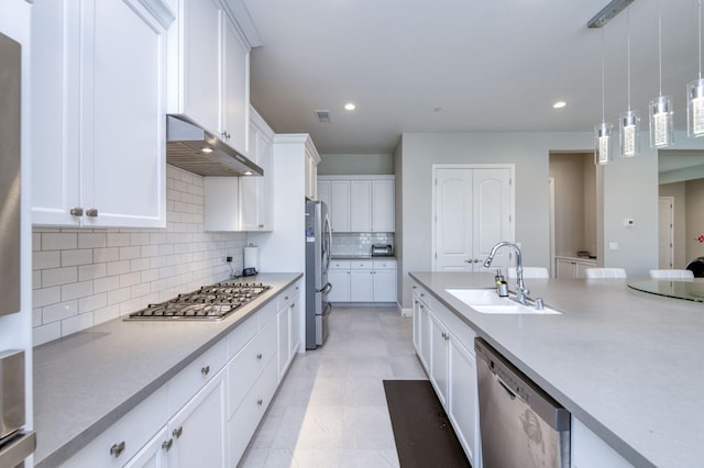 kitchen featuring pendant lighting, stainless steel appliances, light countertops, a sink, and under cabinet range hood