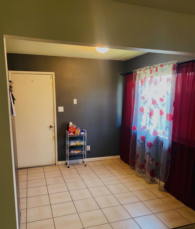 spare room with baseboards and light tile patterned floors