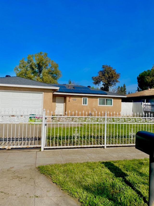 ranch-style house with driveway, a fenced front yard, an attached garage, roof mounted solar panels, and stucco siding