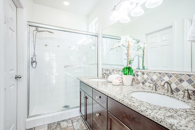 full bathroom featuring tasteful backsplash, a sink, and a shower stall