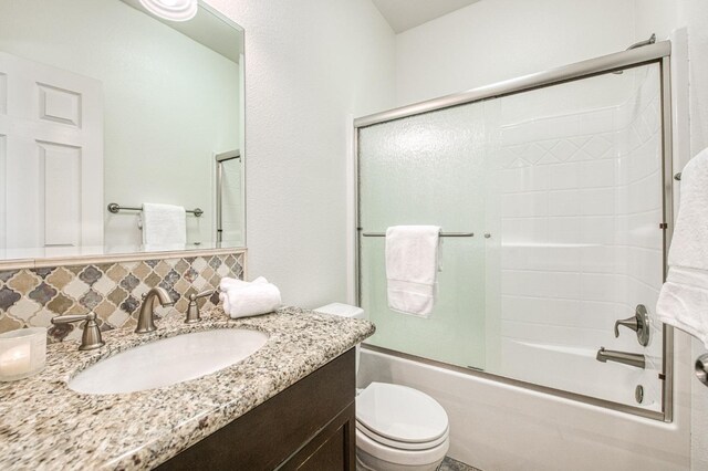 full bathroom with toilet, enclosed tub / shower combo, backsplash, and vanity