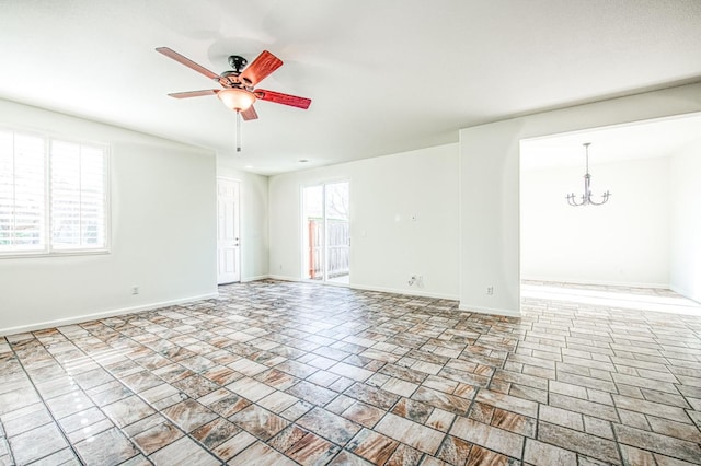 unfurnished room with baseboards and ceiling fan with notable chandelier