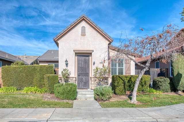 view of front facade featuring stone siding, a tile roof, and stucco siding