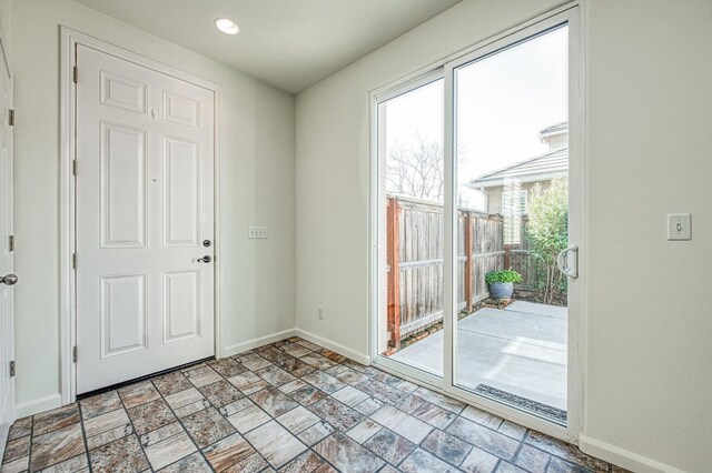 entryway featuring stone finish flooring and baseboards