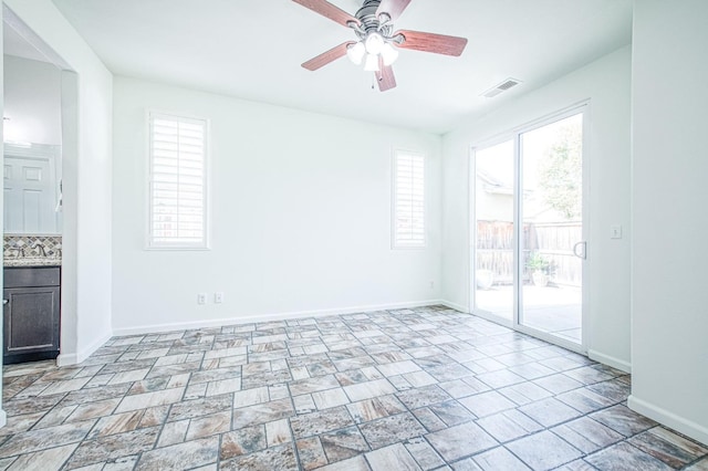 unfurnished room featuring a ceiling fan, visible vents, and baseboards