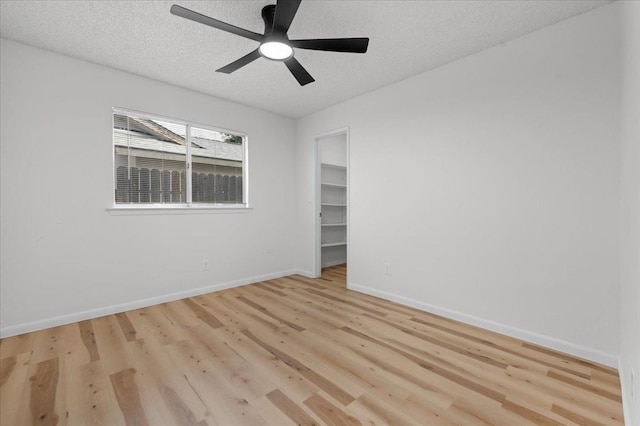 unfurnished room with light wood finished floors, a ceiling fan, baseboards, and a textured ceiling