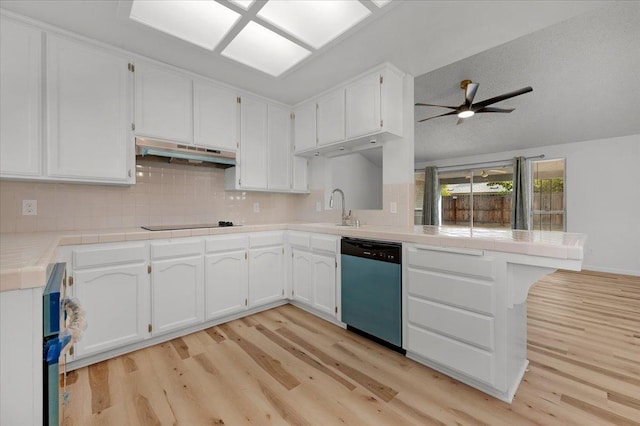 kitchen featuring under cabinet range hood, a peninsula, white cabinets, light countertops, and stainless steel dishwasher