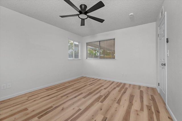 spare room featuring light wood-style floors, a textured ceiling, baseboards, and a ceiling fan