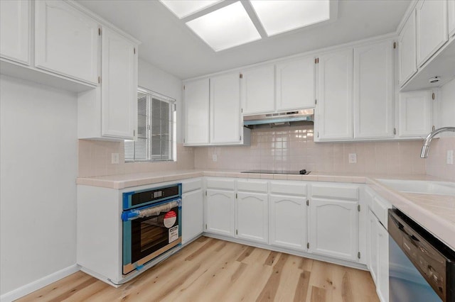 kitchen with white cabinetry, a sink, stainless steel oven, under cabinet range hood, and dishwashing machine