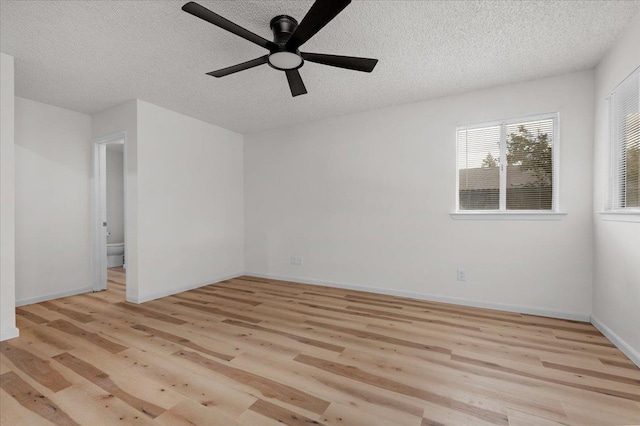 spare room featuring baseboards, ceiling fan, a textured ceiling, and light wood finished floors