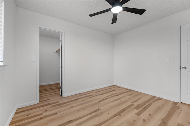 spare room with light wood-style flooring, baseboards, and a textured ceiling