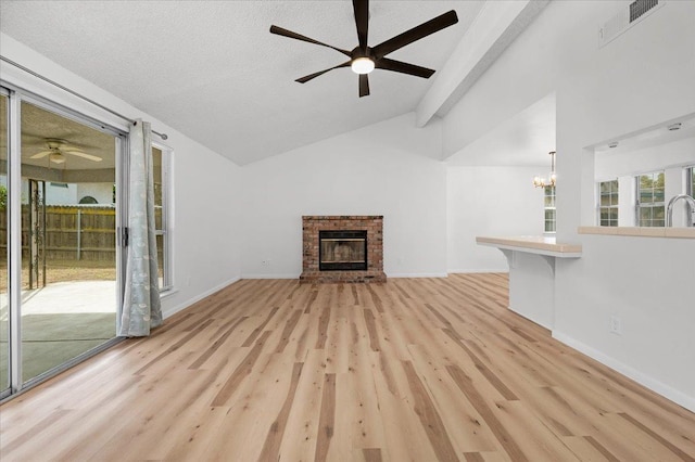 unfurnished living room featuring baseboards, visible vents, vaulted ceiling, light wood-type flooring, and a brick fireplace