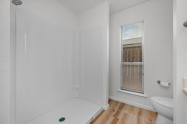 full bath with a shower, wood finished floors, toilet, and baseboards