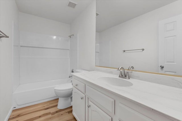 bathroom featuring visible vents, toilet, wood finished floors, vanity, and washtub / shower combination