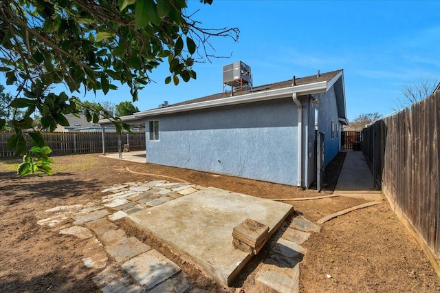 rear view of property featuring a patio, central air condition unit, a fenced backyard, and stucco siding