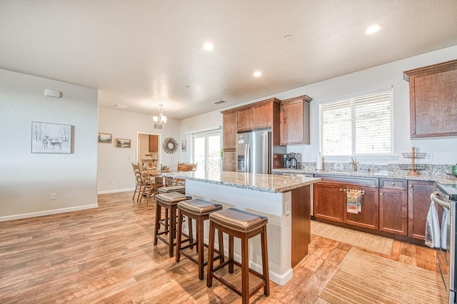 36105 Cressman Rd, Shaver Lake, CA 93664 - kitchen with stainless steel fridge with ice dispenser, a center island, a kitchen breakfast bar, light stone counters, and a sink