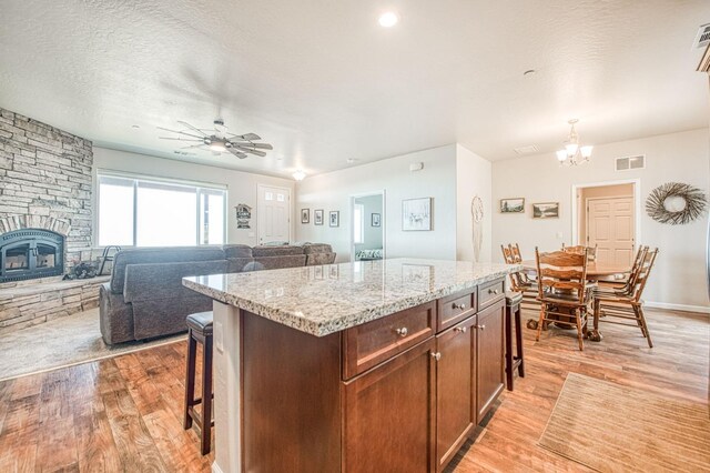 kitchen with light wood-type flooring, a fireplace, and a kitchen bar