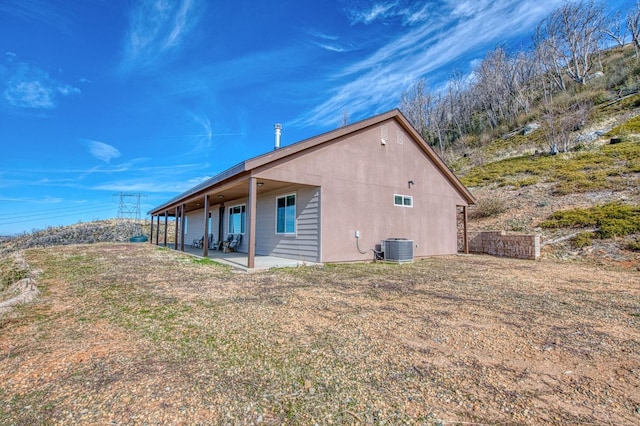 view of side of property featuring central AC, a patio area, and stucco siding