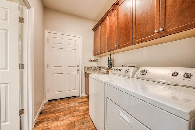 washroom featuring light wood-style flooring, washer and clothes dryer, cabinet space, and baseboards