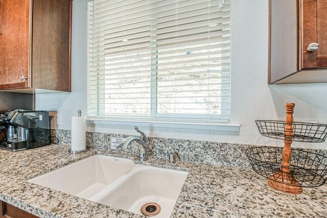 interior details with light stone countertops, brown cabinetry, and a sink