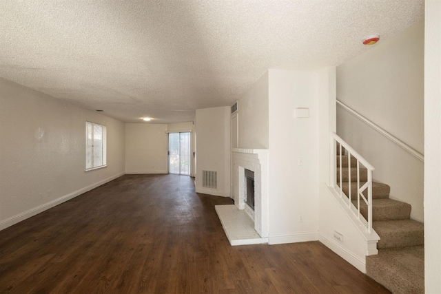 unfurnished living room featuring stairs, visible vents, dark wood finished floors, and a fireplace