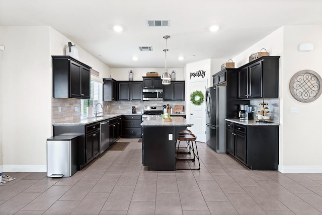 kitchen with a center island, a breakfast bar area, visible vents, decorative backsplash, and appliances with stainless steel finishes