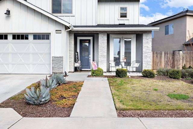 view of exterior entry featuring a porch, board and batten siding, fence, a garage, and stone siding