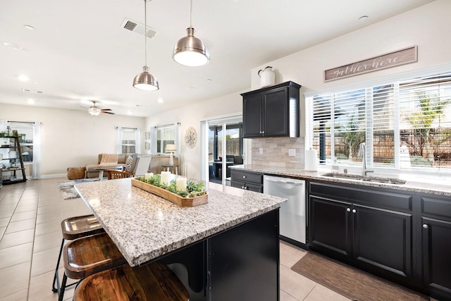 kitchen with visible vents, dishwasher, dark cabinets, a sink, and light tile patterned flooring