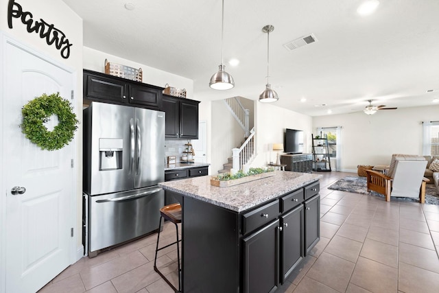 kitchen featuring light tile patterned floors, dark cabinets, visible vents, and stainless steel fridge with ice dispenser