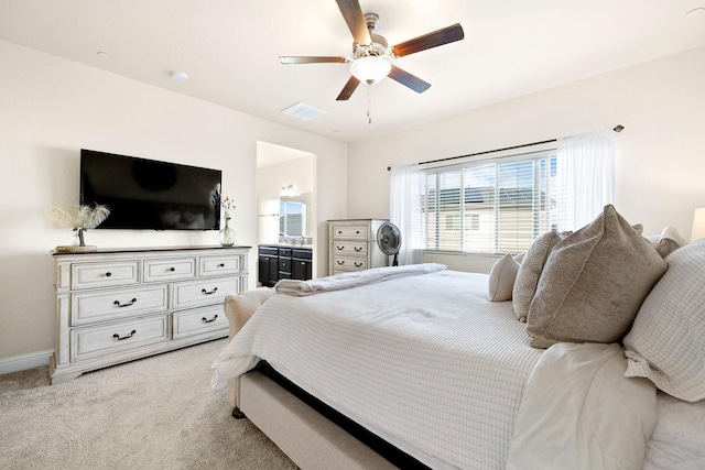 bedroom featuring visible vents, baseboards, a ceiling fan, light colored carpet, and ensuite bath