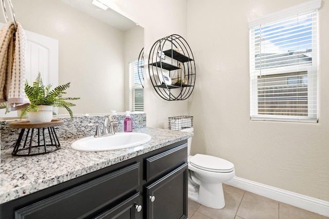 half bathroom featuring toilet, vanity, baseboards, and tile patterned floors