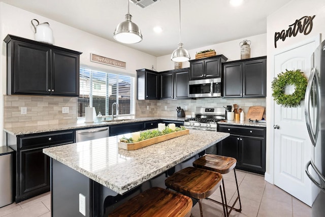 kitchen with appliances with stainless steel finishes, light tile patterned flooring, a sink, and dark cabinets