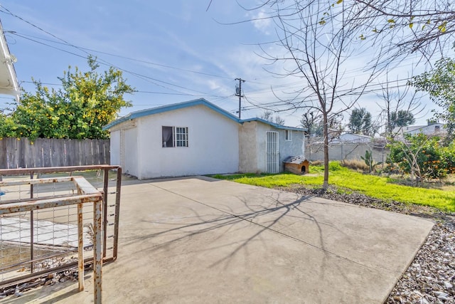 back of property with concrete driveway, a patio area, a fenced backyard, and stucco siding