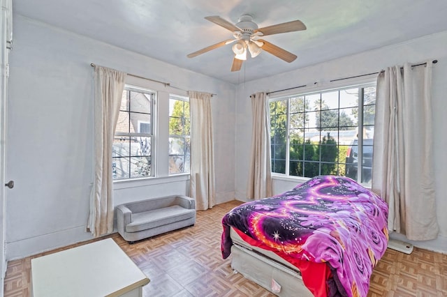 bedroom with multiple windows, a ceiling fan, and baseboards