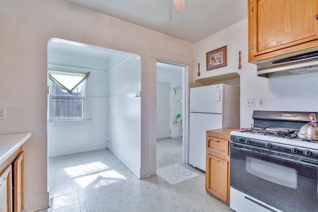 kitchen with ceiling fan, light countertops, freestanding refrigerator, light floors, and gas range