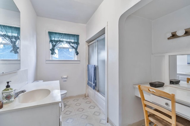 bathroom featuring toilet, baseboards, combined bath / shower with glass door, and vanity