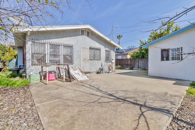 exterior space with a patio, fence, and stucco siding