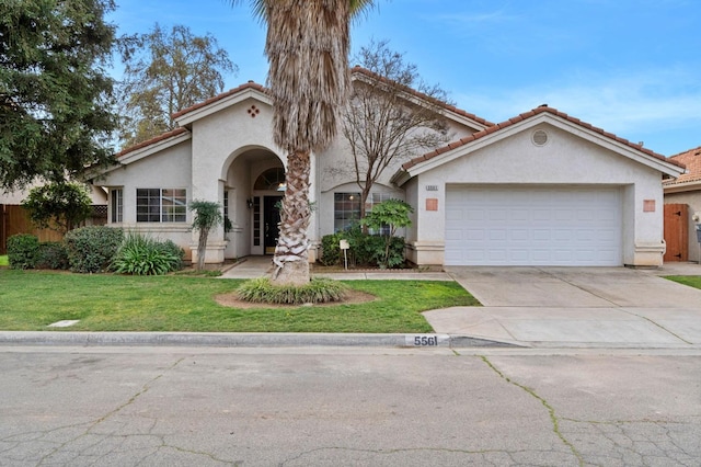 mediterranean / spanish house featuring a tile roof, stucco siding, an attached garage, driveway, and a front lawn