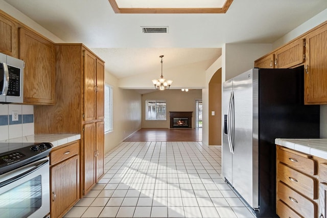 kitchen featuring lofted ceiling, light tile patterned flooring, tile counters, and stainless steel appliances