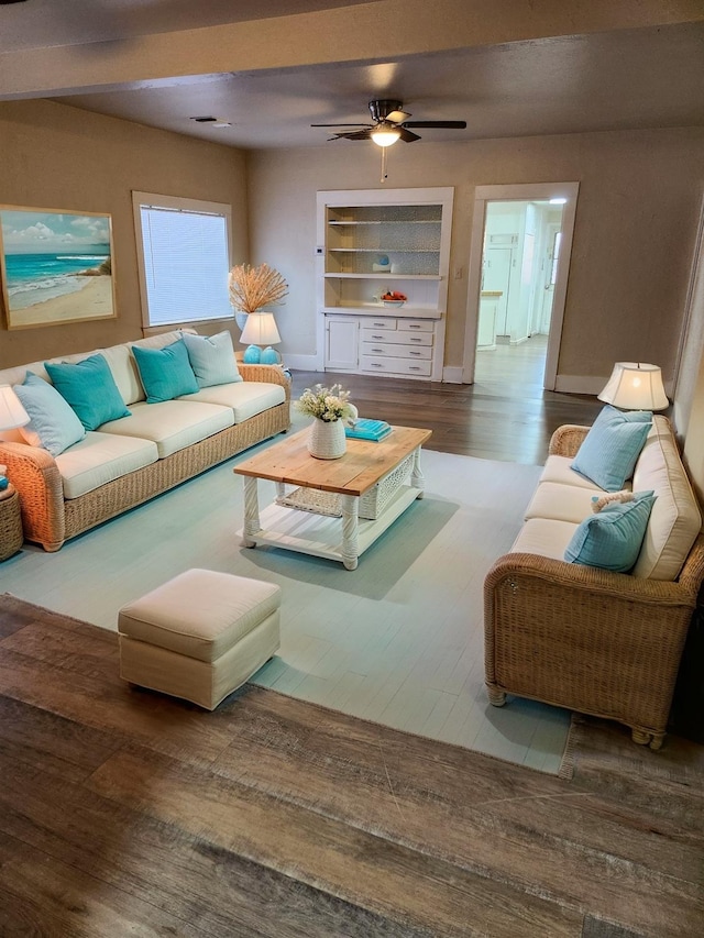 living area featuring ceiling fan, built in shelves, baseboards, and wood finished floors