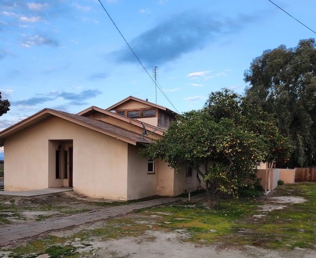 view of side of property featuring fence and stucco siding