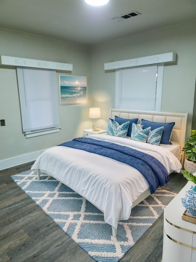 bedroom with baseboards, visible vents, and wood finished floors