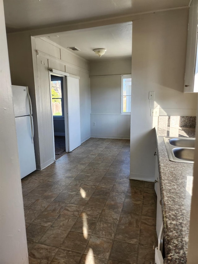 kitchen with a wealth of natural light, visible vents, a sink, and freestanding refrigerator