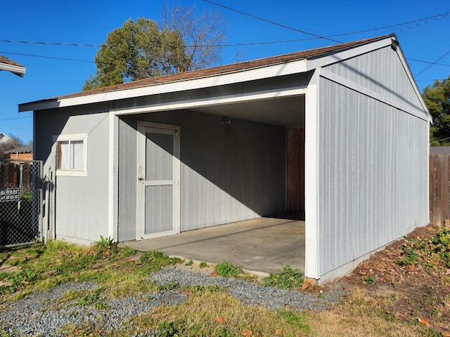 view of outbuilding with a carport, an outbuilding, and fence