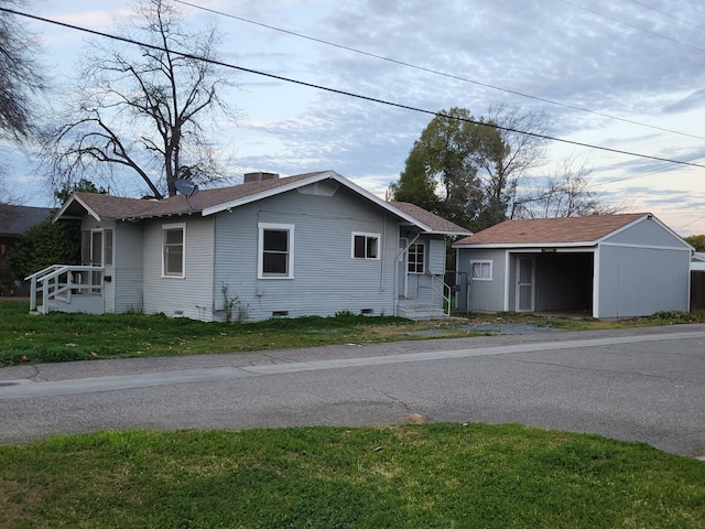 view of front of home featuring roof with shingles, crawl space, a chimney, and an outdoor structure