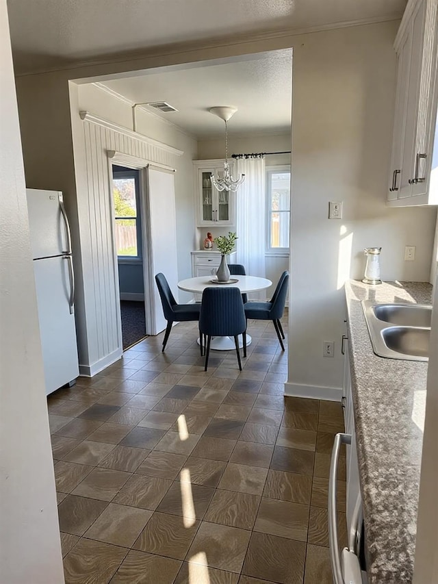 dining space featuring a notable chandelier, crown molding, and baseboards