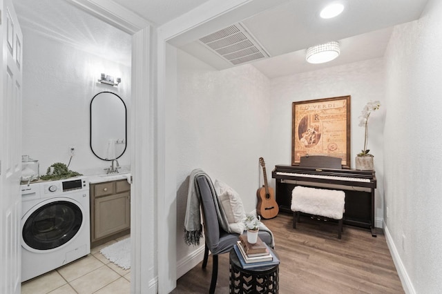 clothes washing area with washer / clothes dryer, cabinet space, visible vents, a sink, and baseboards